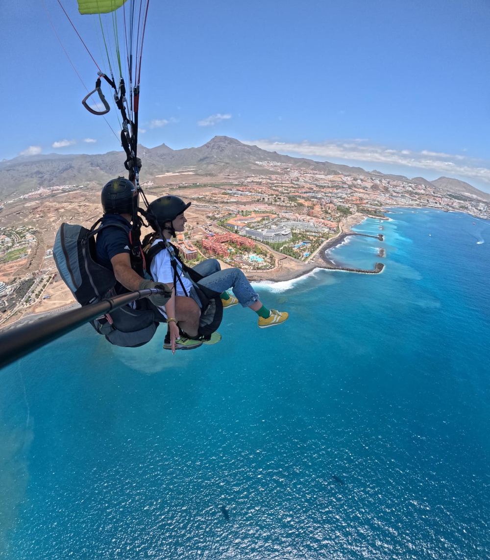 Pasajero contemplando las vistas de la costa y el mar durante el vuelo en parapente